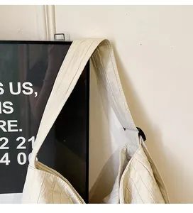 Détail d'un sac en nylon crème avec une bandoulière réglable et une texture plissée