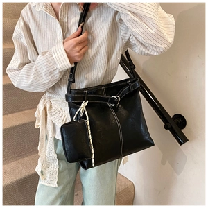 Detail of black leather crossbody tote with contrast stitching and matching mini coin purse