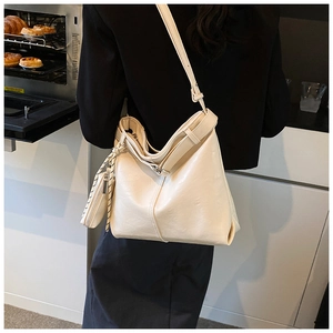 Detail of a minimalist cream hobo tote bag featuring side knot design and small pouch