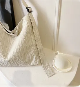 Détail du sac cabas blanc cassé avec texture plissée et bandoulière noire réglable