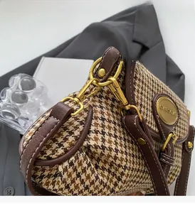Detail of vintage houndstooth fabric and brown leather strap with golden metal hardware
