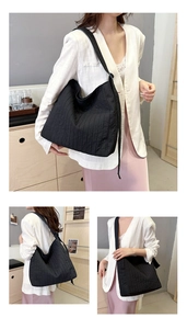 Détail de la texture matelassée noire et du design plissé vertical du grand sac cabas