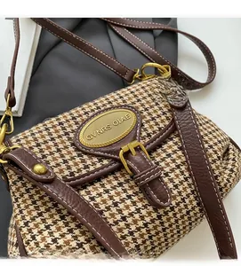 Detail view of vintage houndstooth fabric with brown lychee leather and gold logo plaque
