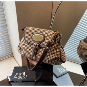 Detail of vintage houndstooth shoulder bag with golden logo plaque and brown leather trim