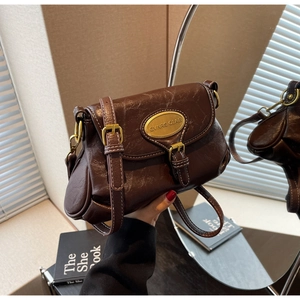 Close-up of dark brown vintage faux leather bag texture with golden oval metal buckle detail