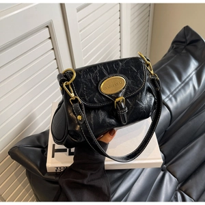 Detail of vintage black pleated shoulder bag with gold metal buckle and engraved plaque