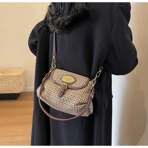 Close-up of a vintage houndstooth crossbody bag with brown leather trim and gold buckle