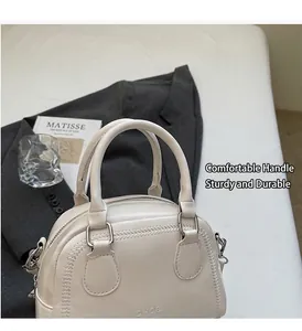 Close-up of cream-white leather pillow bag with V-shaped stitching and dual handles
