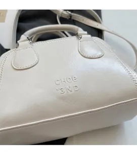 Detail of cream-colored pillow bag showing soft textured leather and embossed logo