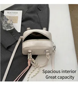 Detail of beige minimalist pillow bag with colorful braided cord charm on suit jacket