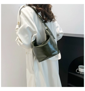 Detail shot of the dark green glossy patent leather hobo bag on a shoulder for women