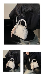 Detailed view of an off-white small crossbody handbag with tassel and top handle