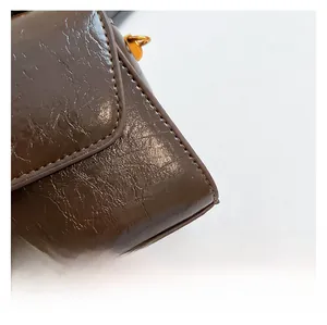 Details der dunkelbraunen Ölwachs-Ledertextur und goldener Metallschnalle am Bag