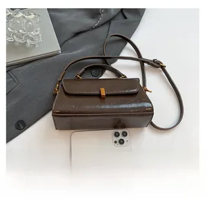 Detailansicht der dunkelbraunen glänzenden Ledertasche mit Retro-Metallschnalle und Gurt