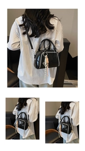 Model carrying stylish black retro crossbody handbag with decorative stitching details