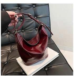 Detail of adjustable golden metal buckle on dark red patent leather shoulder bag