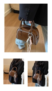 Detailed macro view of a brown retro handbag with white stitching and rope charms