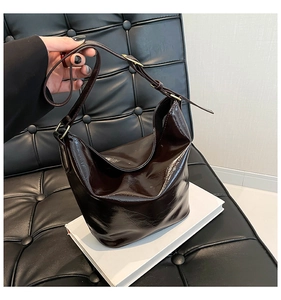 Detail of glossy hobo bag with adjustable strap on white books against a dark background