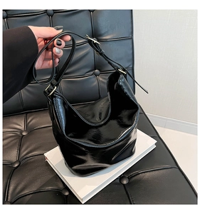 Detail of glossy black patent leather shoulder bag with adjustable golden metal buckle