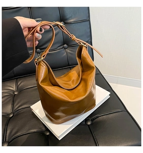 Detail view of caramel faux leather hobo bag with gold buckle on a white book