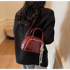 Close-up of dark red boston bag with white herringbone stitching and logo detail