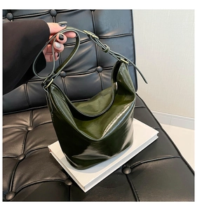 Detail of dark green glossy hobo bag with adjustable strap and gold metal hardware