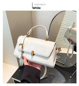 Detail der weißen Vintage-Ledertasche mit goldener Zylinderschließe und Tragegriff