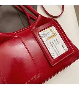 Detail of red glossy patent leather bag showing stitching and side card slot with dog ID tag