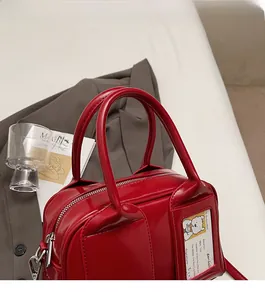 Detail of red glossy tote bag with reinforced handles and clear exterior card slot
