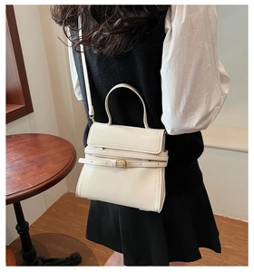 Détail d'un sac bandoulière crème avec sangle décorative et boucle dorée élégante