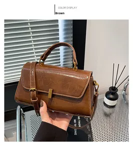 Nahaufnahme der braunen Vintage-Handtasche mit glänzender Faltenoptik und Goldschnalle
