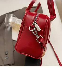 Close-up of a red patent leather tote bag with silver zippers and a sleek handle