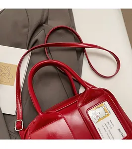 Detail of red patent leather bowling bag with transparent card slot and slim strap