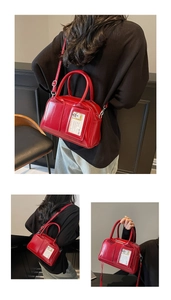 Detail view of red glossy crossbody bag with tubular handles and card slot window