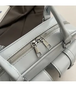 Detailed macro view of silver dual-zipper closure on a light blue leather Boston bag