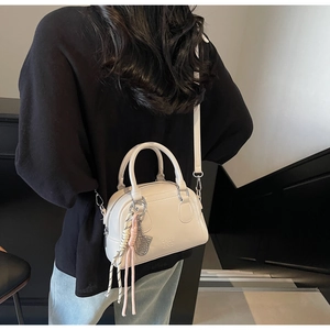 Rear view of model wearing a white mini pillow bag with silver tennis racket charm
