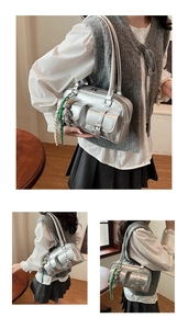 Detailed view of silver metallic multi-pocket shoulder bag with decorative charms and hardware