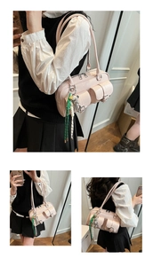 Detail of light pink multi-pocket underarm bag with silver bear pendant and woven charm