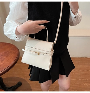 Gros plan d'un sac à bandoulière minimaliste blanc crème avec détail de boucle élégante