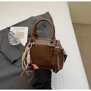 Detail of dark brown vintage Boston bag with white stitching and braided charm