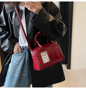 Detail of red glossy leather crossbody bag with clear card slot on black trench coat