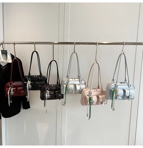 Row of colorful glossy Boston bags with bear charms and decorative buckle straps