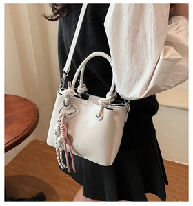 Detail of white leather bucket bag featuring a decorative pink and striped woven rope handle