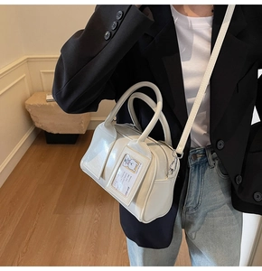 Detailed side view of white glossy bowling handbag with bear card detail on model