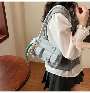 Detail view of a light blue Boston underarm bag with double front pockets and bear charm