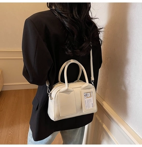 Detail of cream bowling bag showing card slot and detachable crossbody strap styling