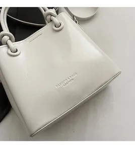 Close-up of cream faux leather bucket bag featuring fashion and bags embossed text