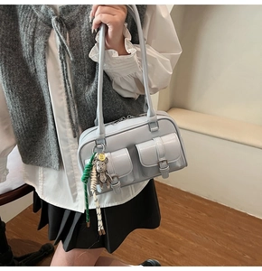 Dettaglio borsa Boston azzurra con tasche a fibbia e portachiavi a forma di orsetto