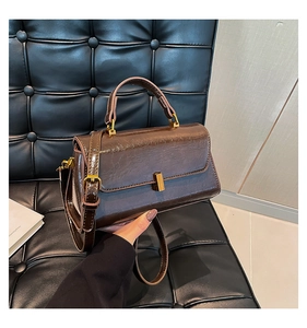 Makro-Detail der braunen Ledertasche mit glänzendem Finish und goldenem Metalldrehverschluss