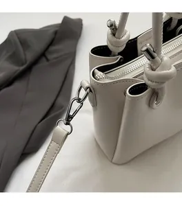 Detailed close-up of premium cream bucket bag featuring silver hardware and knotted handle